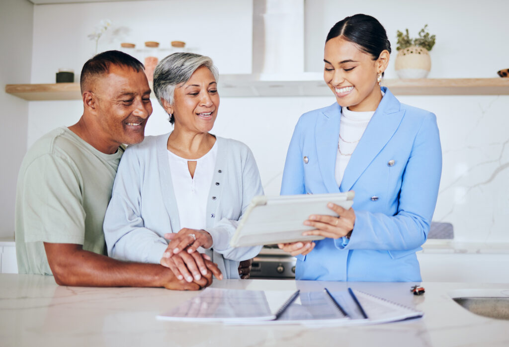 Wellington Group loan signing agent explaining documents to senior couple during home loan signing appointment"